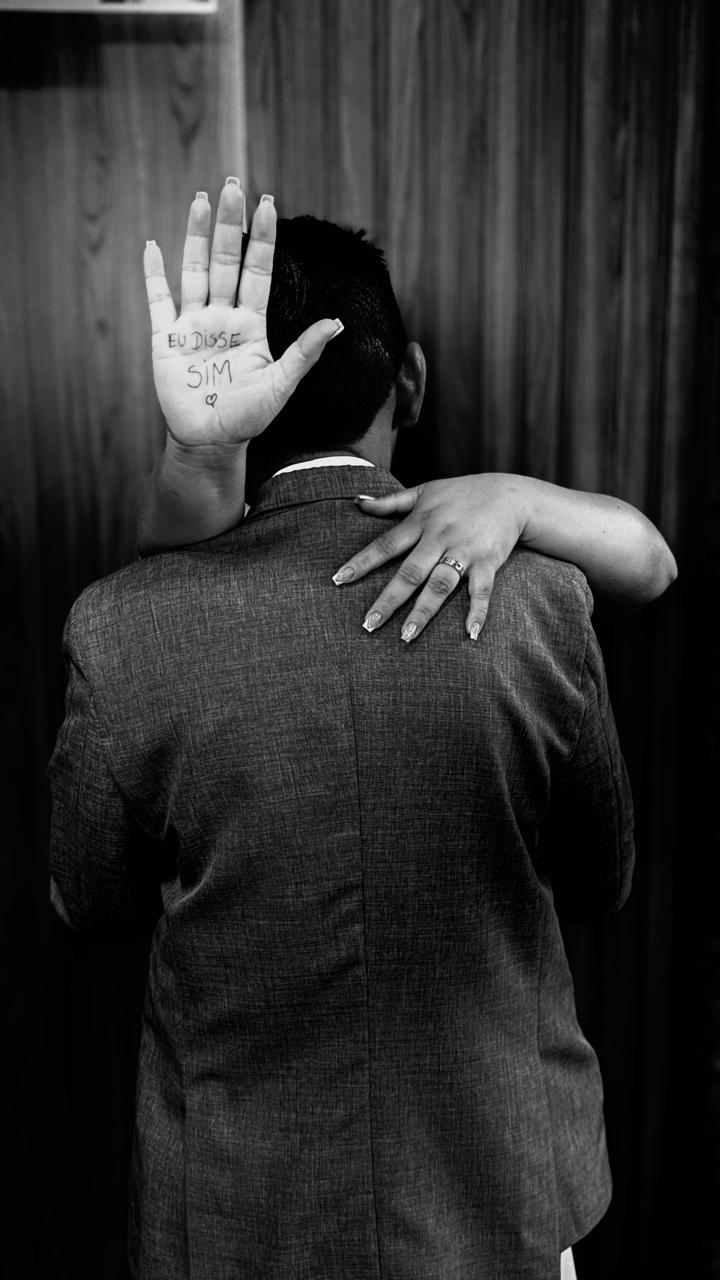 Abraço do casal com a aliança em destaque, em preto e branco