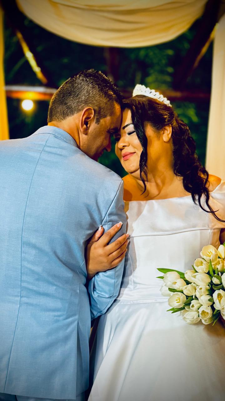 Casal de testa encostada, sorrindo durante a cerimônia