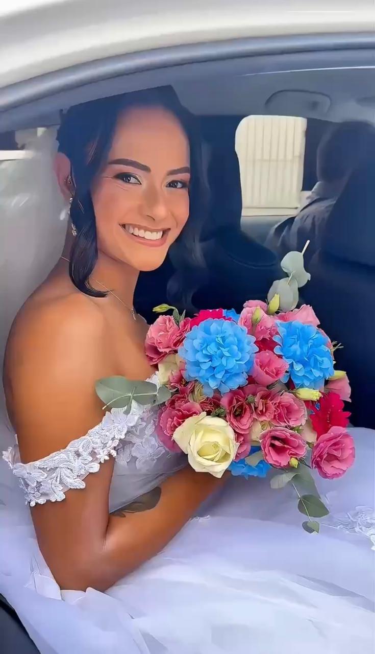 Noiva sorrindo dentro do carro com buquê colorido